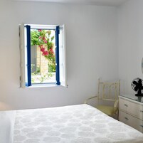 Un dormitorio con cama, una silla, cómoda y una ventana con cortinas azules.