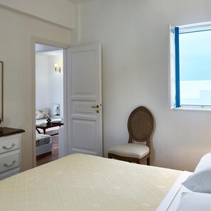A bedroom with a bed, a chair, a dresser, and a door leading to another room.