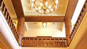Una imponente escalera con balaustrada de madera, un candelabro decorativo y vistas al piso superior.