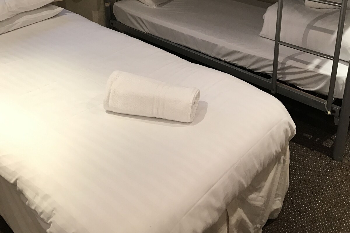 Un lit superposé avec une literie blanche et une serviette enroulée sur le lit du bas.