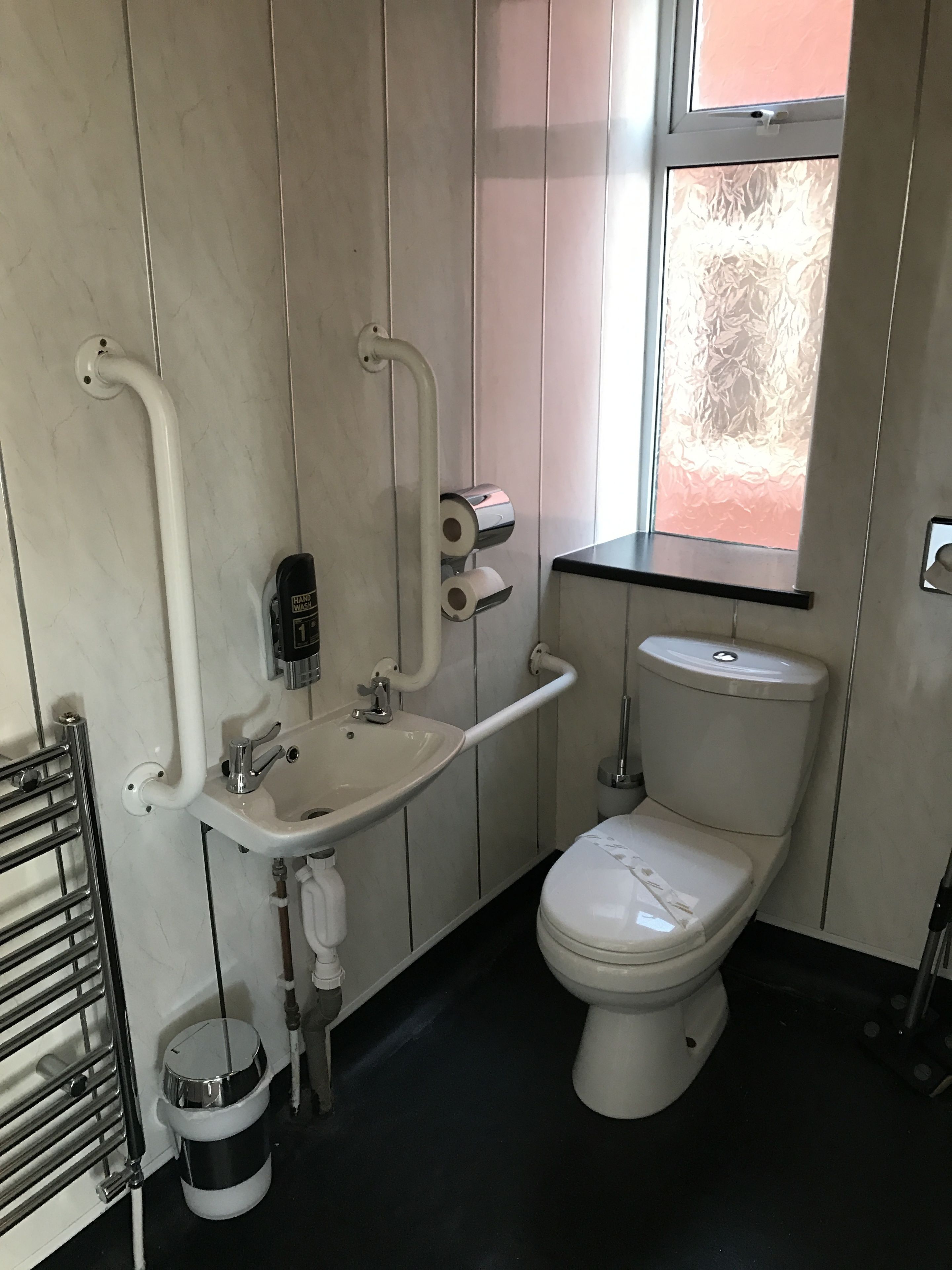 A modern bathroom with a white sink, toilet, and hand dryer.