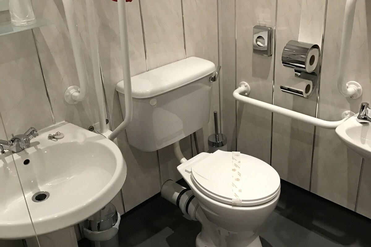 Une salle de bain moderne avec des toilettes blanches, un lavabo et un espace douche.