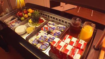 Un buffet proposant une variété d’aliments, notamment des fruits, du yaourt et du jus de fruits.