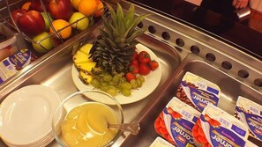 A kitchen sink with fruits, a bowl of orange juice, and cereal boxes. - Queens Plaza Hotel (Blackpool)