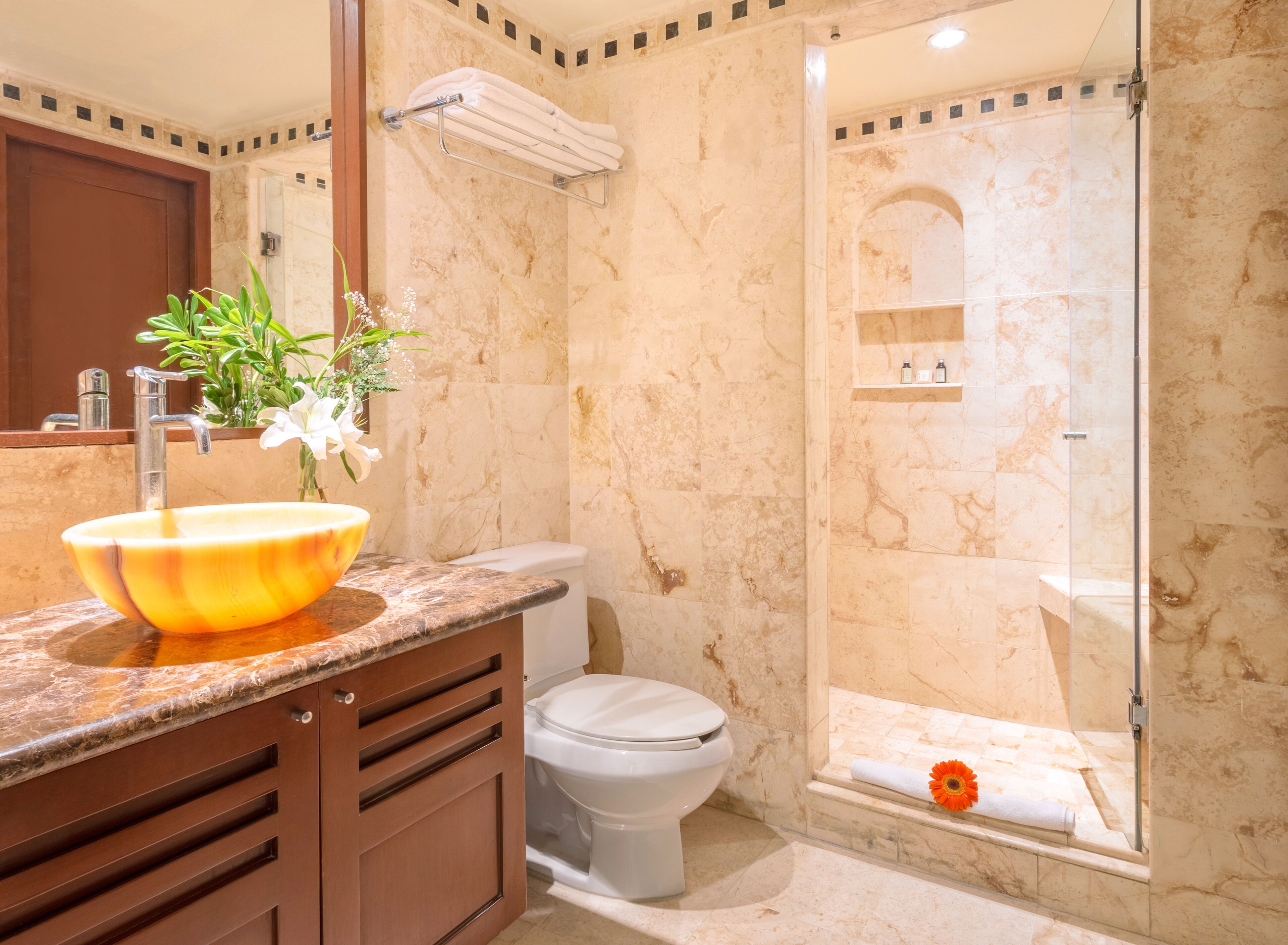 Een badkamer met een marmeren wastafel, toilet en een douche met glazen wanden.