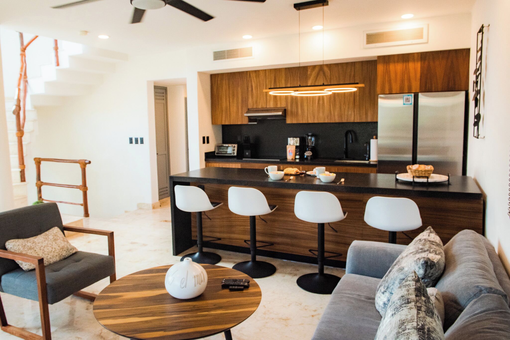 A modern kitchen with a central island, bar stools, and a built-in refrigerator.