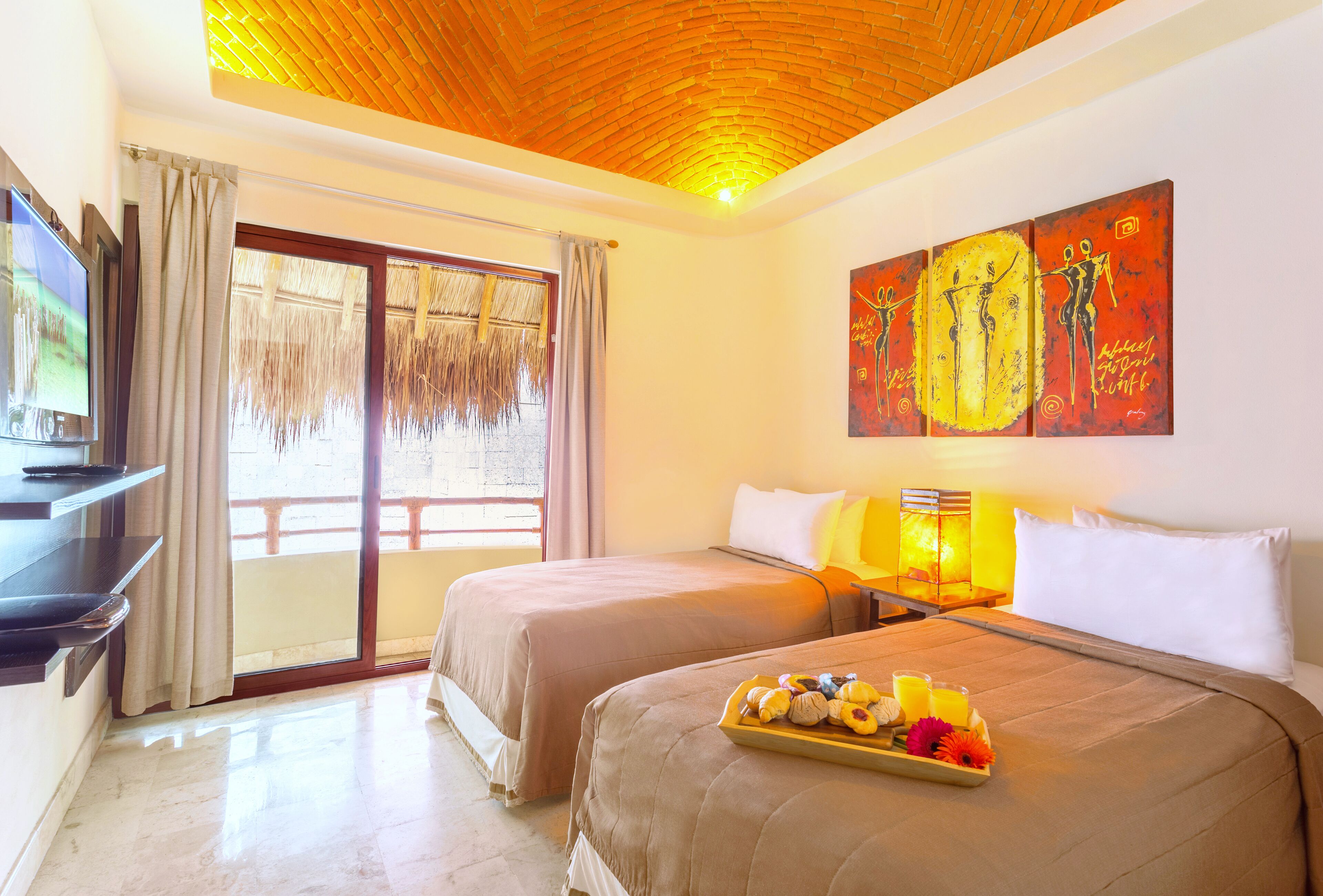 A hotel room with two beds, a TV, a large window with curtains, and a painting on the wall.