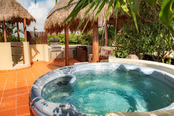 A hot tub surrounded by a patio area with a grill and seating. - Maya Villa Condo Hotel & Beach Club (Playa del Carmen)