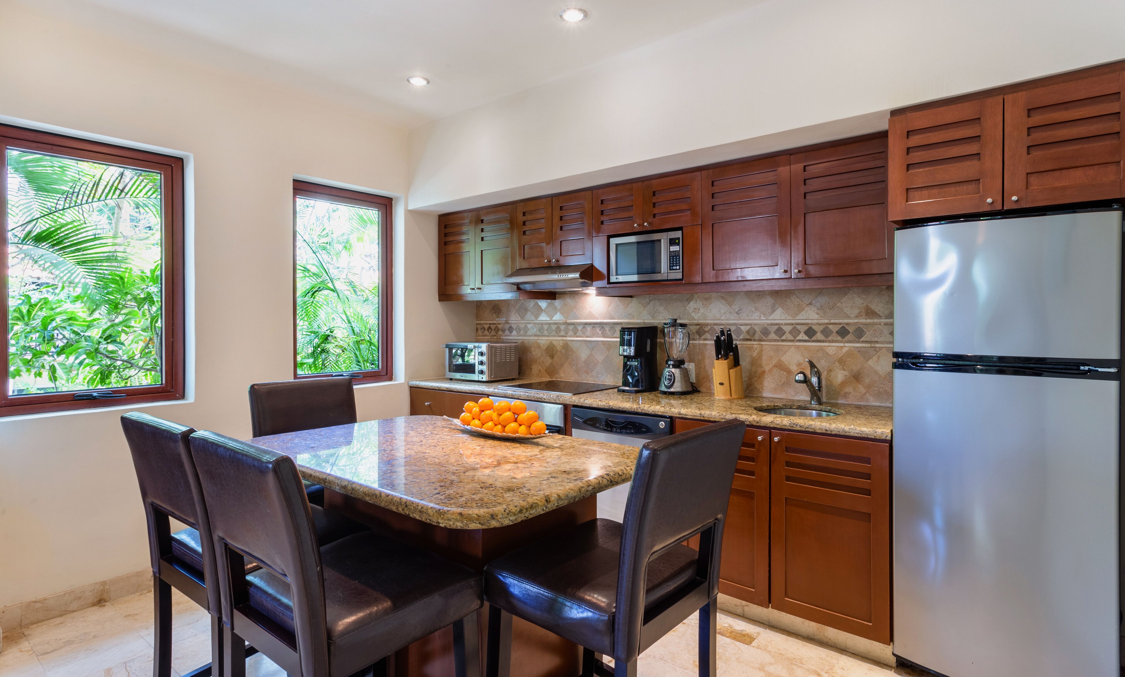 A modern kitchen with wooden cabinets, a granite countertop, and a stainless steel refrigerator.