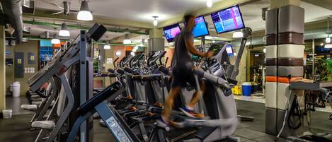 A gym with multiple treadmills, exercise equipment, and digital screens displaying workout information.