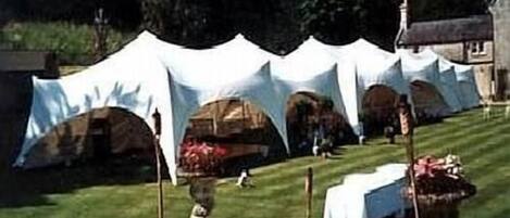Un área al aire libre con carpas, un césped y un edificio en el fondo.
