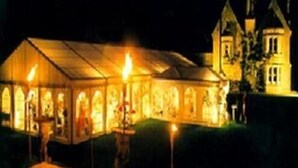 Een grote, verlichte tentachtige constructie met een puntige dak, waarschijnlijk gebruikt voor evenementen of bijeenkomsten.