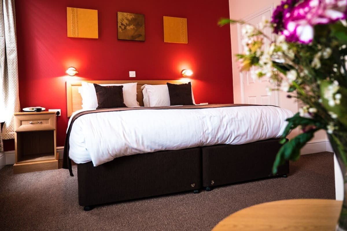 Habitación de hotel con cama, mesitas de noche y decoración en la pared.