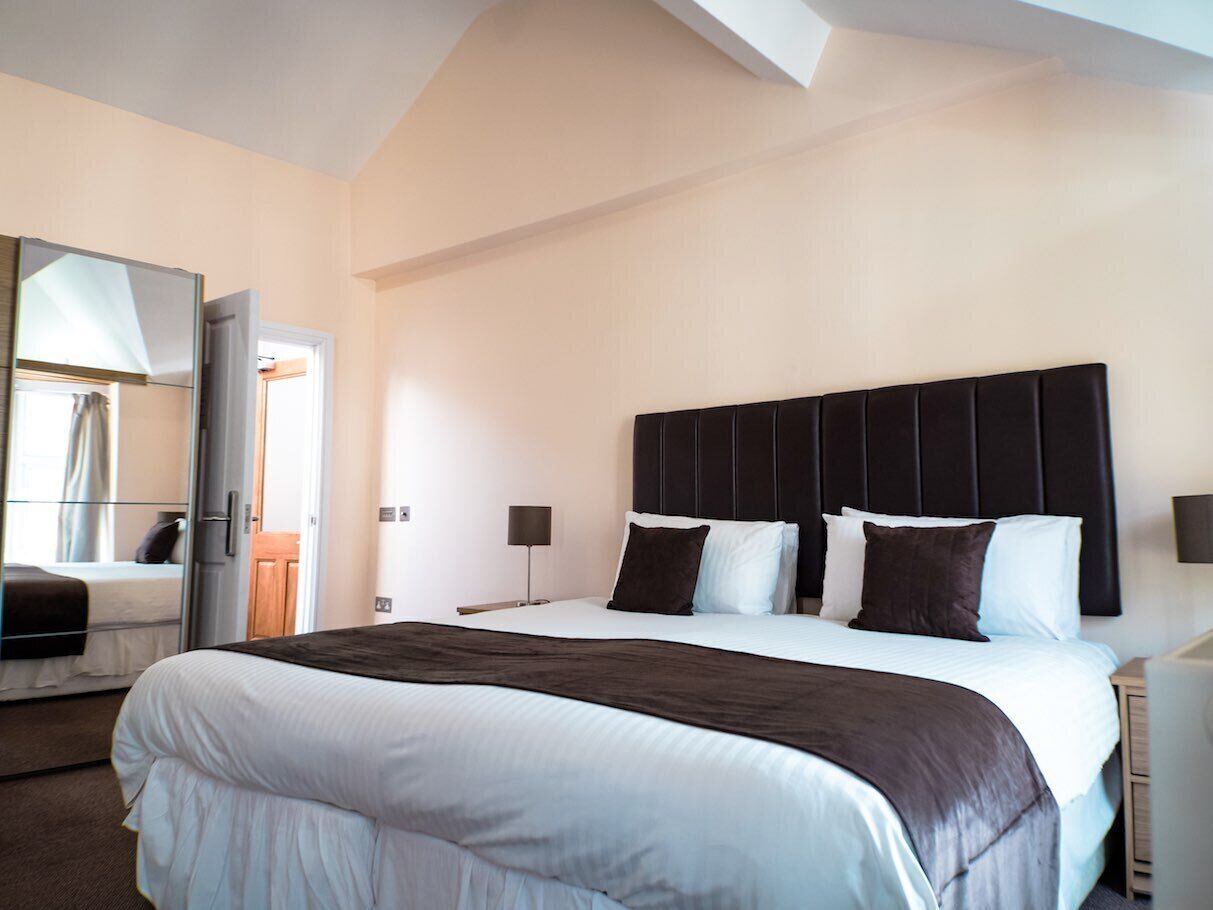 Una habitación de hotel con una cama grande, una mesita de noche, una lámpara y un armario.