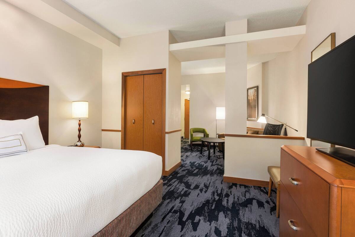 Una habitación de hotel con una cama grande, un escritorio, una silla, un televisor y un armario.