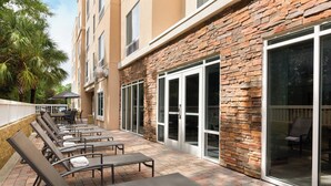 A hotel patio with sun loungers, a covered seating area, and a stone facade.