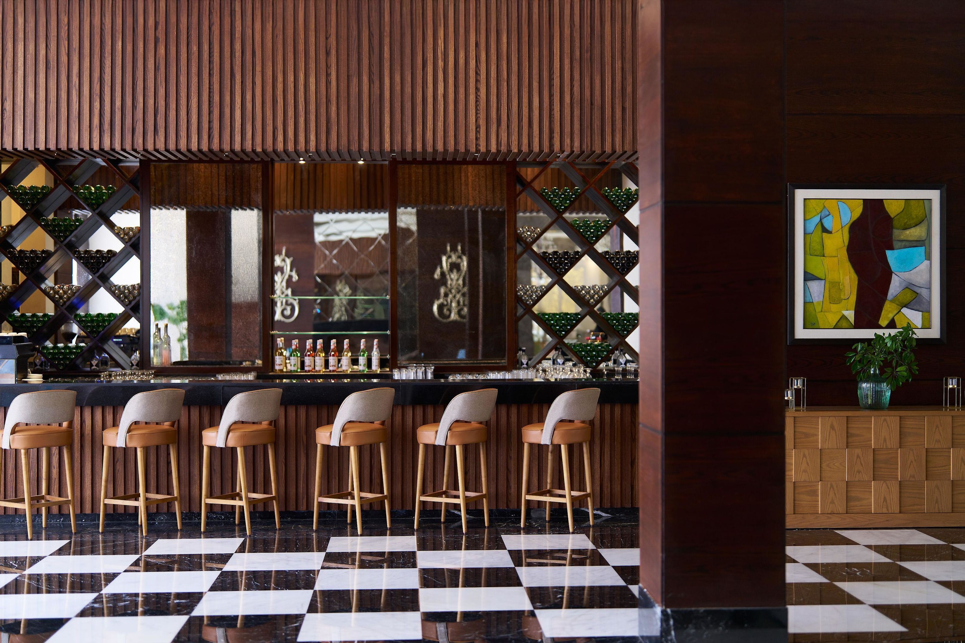 Un área de bar con paneles de madera, piso a cuadros y taburetes.