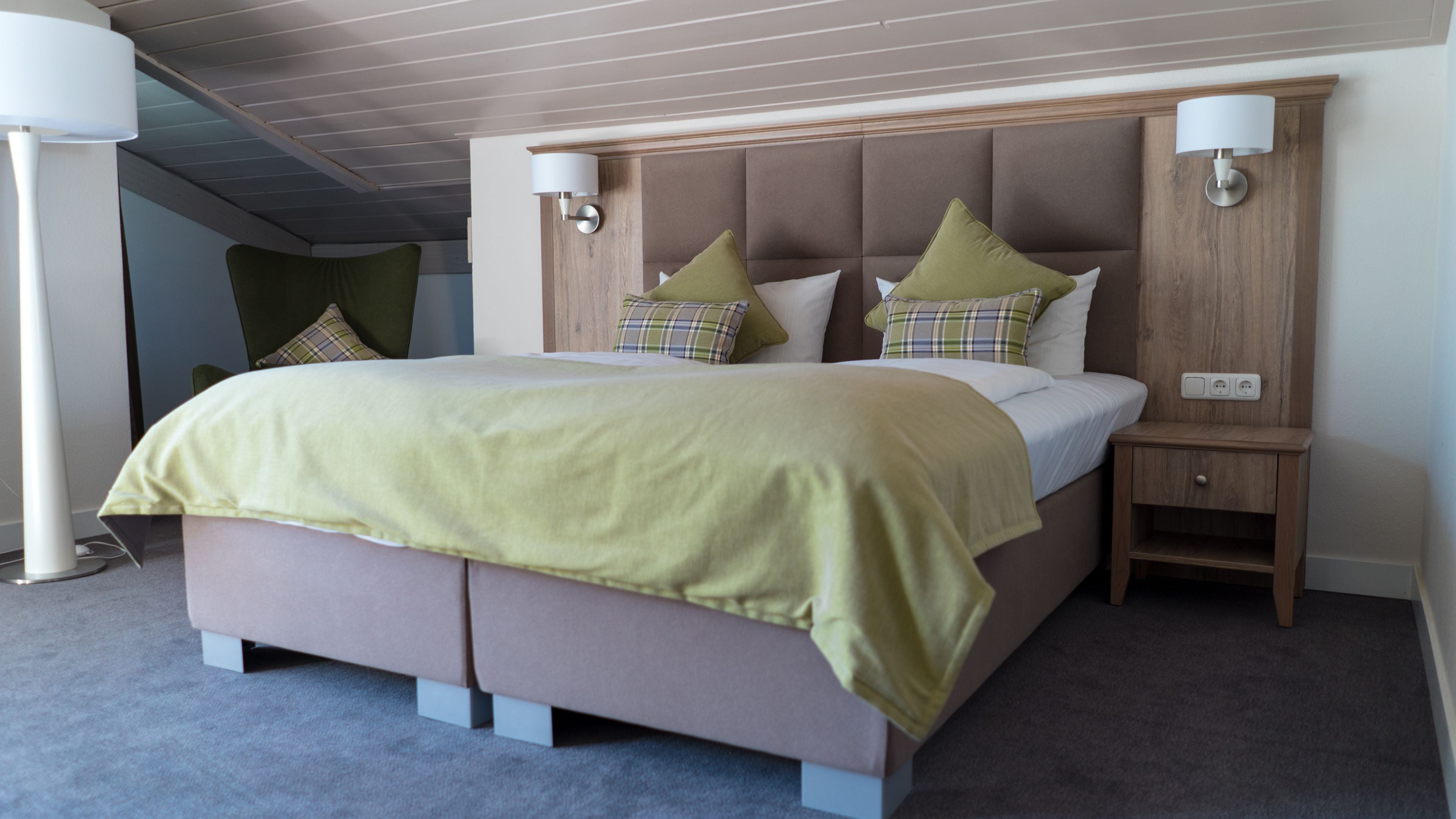 A modern hotel room with a large bed, two bedside tables, and a nightstand.