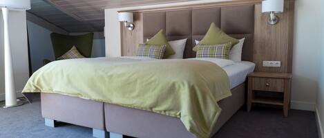 A modern hotel room with a large bed, two bedside tables, and a nightstand.