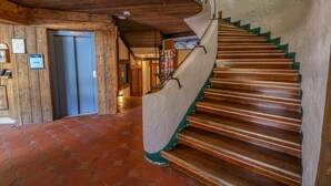 A wooden interior with a spiral staircase, a tiled floor, and an elevator.