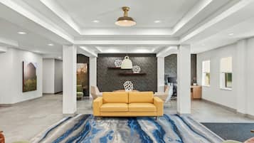 A spacious lobby with a central seating area, a modern ceiling design, and artwork on the walls.