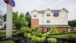 A Fairfield Inn & Suites Marriott hotel with a brick facade, multiple windows, and a well-maintained garden in front.