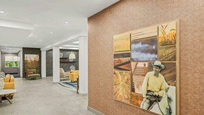 A modern hotel lobby with a large wall mural, seating areas, and a view of the outdoors. - Fairfield Inn & Suites by Marriott Portsmouth Exeter (Exeter)