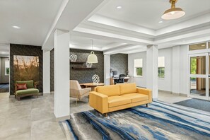 A modern interior with a sofa, chairs, a desk, and a large window. - Fairfield Inn & Suites by Marriott Portsmouth Exeter (Exeter)