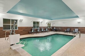 Un espace piscine doté d’un sol carrelé, d’une piscine et de sièges disposés autour de celle-ci.