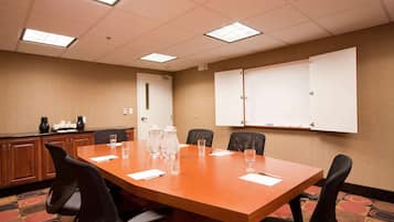 Un salón de conferencias con una mesa de madera, seis sillas, una pizarra y una puerta.