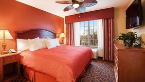 Une chambre d’hôtel avec un grand lit, un ventilateur de plafond, une télévision et une fenêtre avec des rideaux.