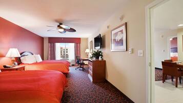 Habitación de hotel con dos camas, un escritorio, una silla, un televisor y una ventana con cortinas.