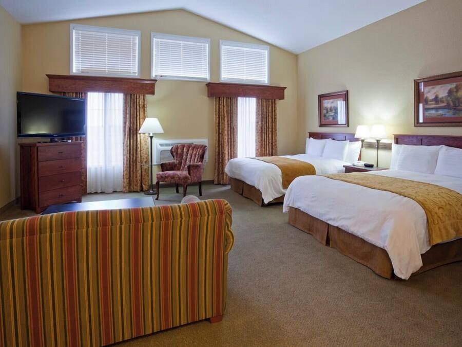 A hotel room with two beds, a television, a desk, and a chair.