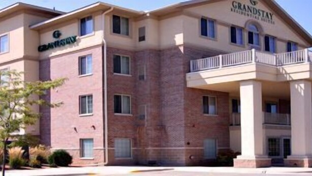 A multi-story hotel with a brick facade, a covered entrance with columns, and a sign reading "GrandStay". - GrandStay Residential Suites Hotel (Faribault)