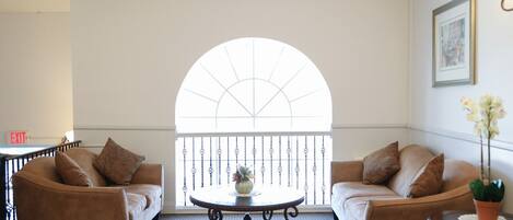 Una habitación con dos sofás, una mesa redonda y un amplio ventanal de arco.