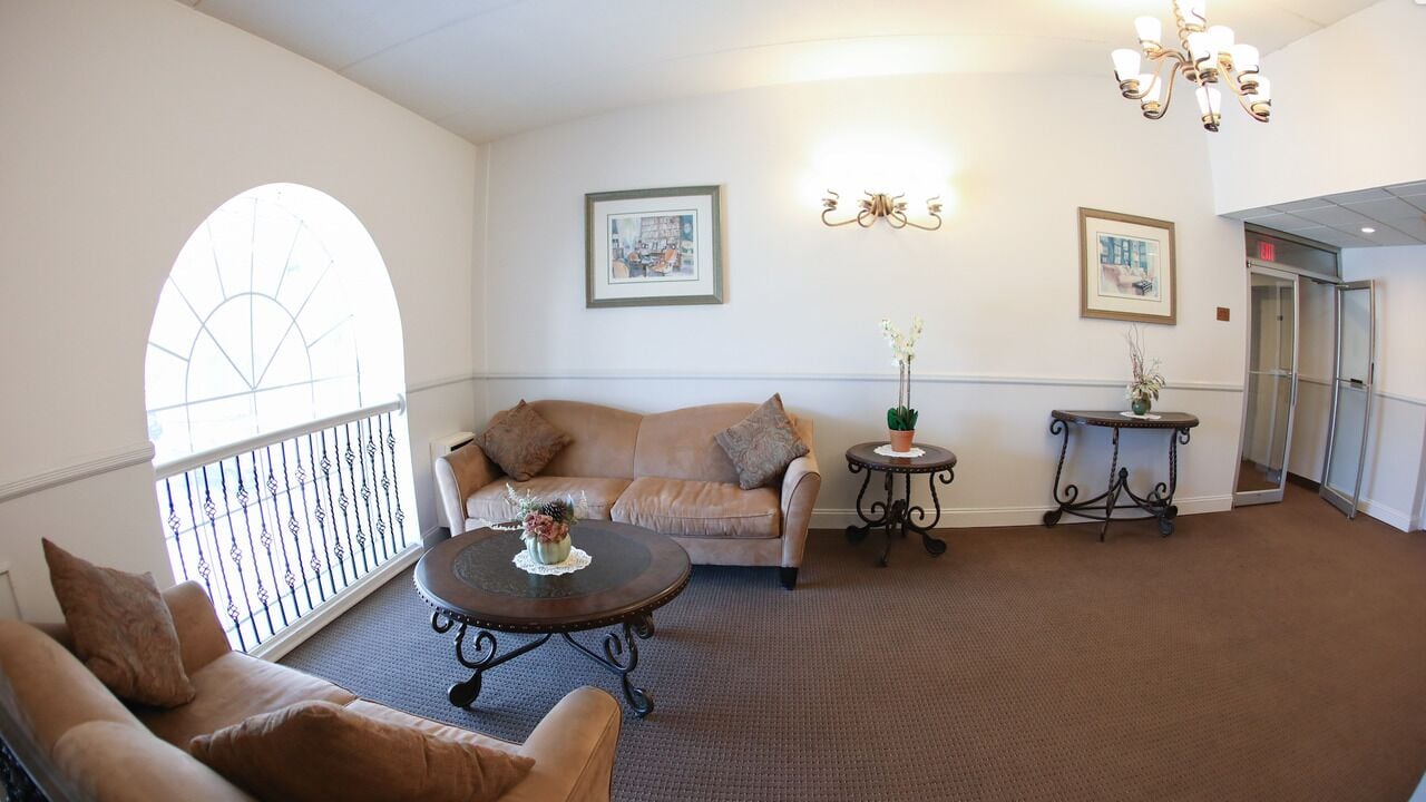 A spacious lobby with a beige sofa, a round coffee table, and two side tables with decorative plants.