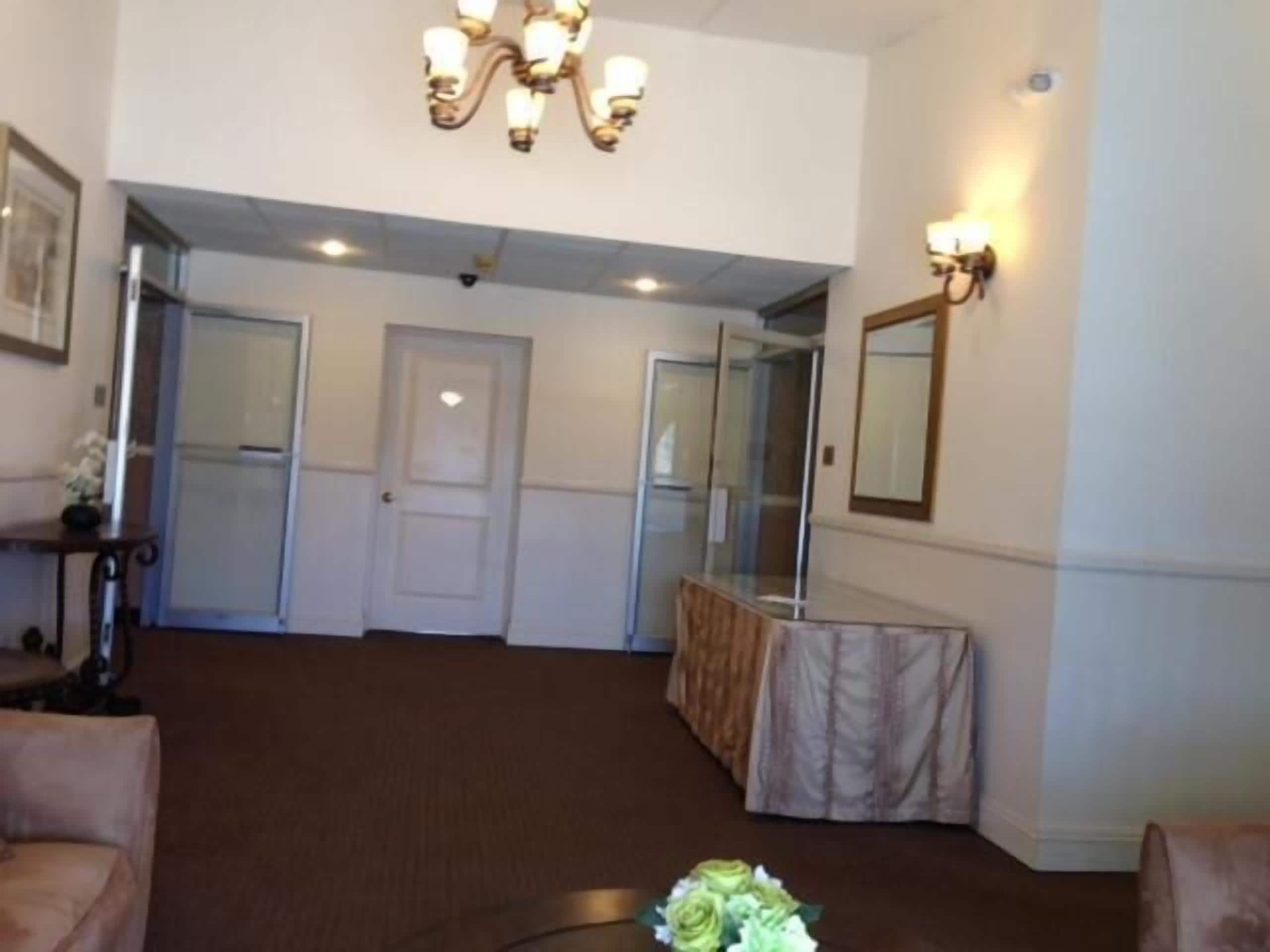 A spacious room with a chandelier, a mirror, and a table with a floral arrangement.