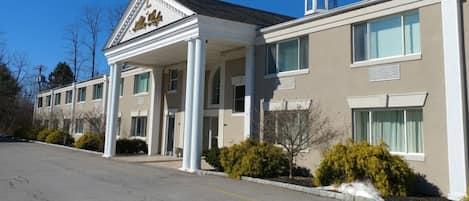 A two-story hotel with a classic facade, large windows, and a central entrance with columns.