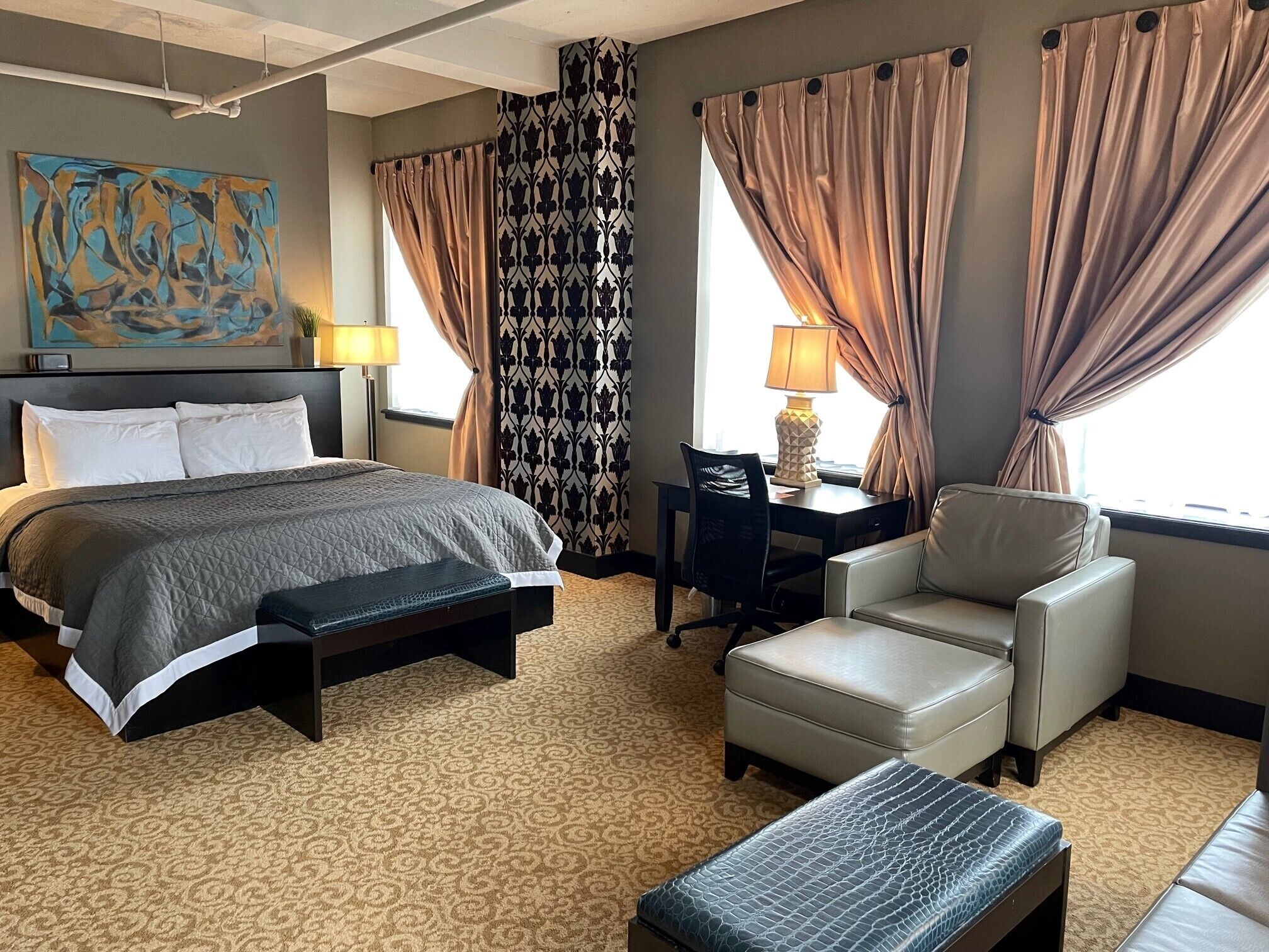 A hotel room with a bed, a desk, a chair, and a sofa.