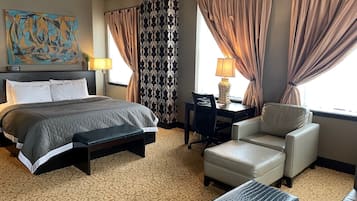 A hotel room with a bed, a desk, a chair, and a sofa.