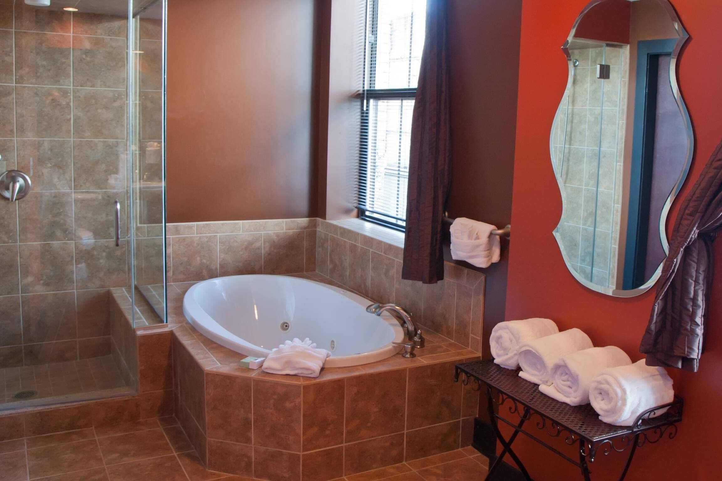 A bathroom with a large bathtub, a glass shower enclosure, and a vanity with towels.