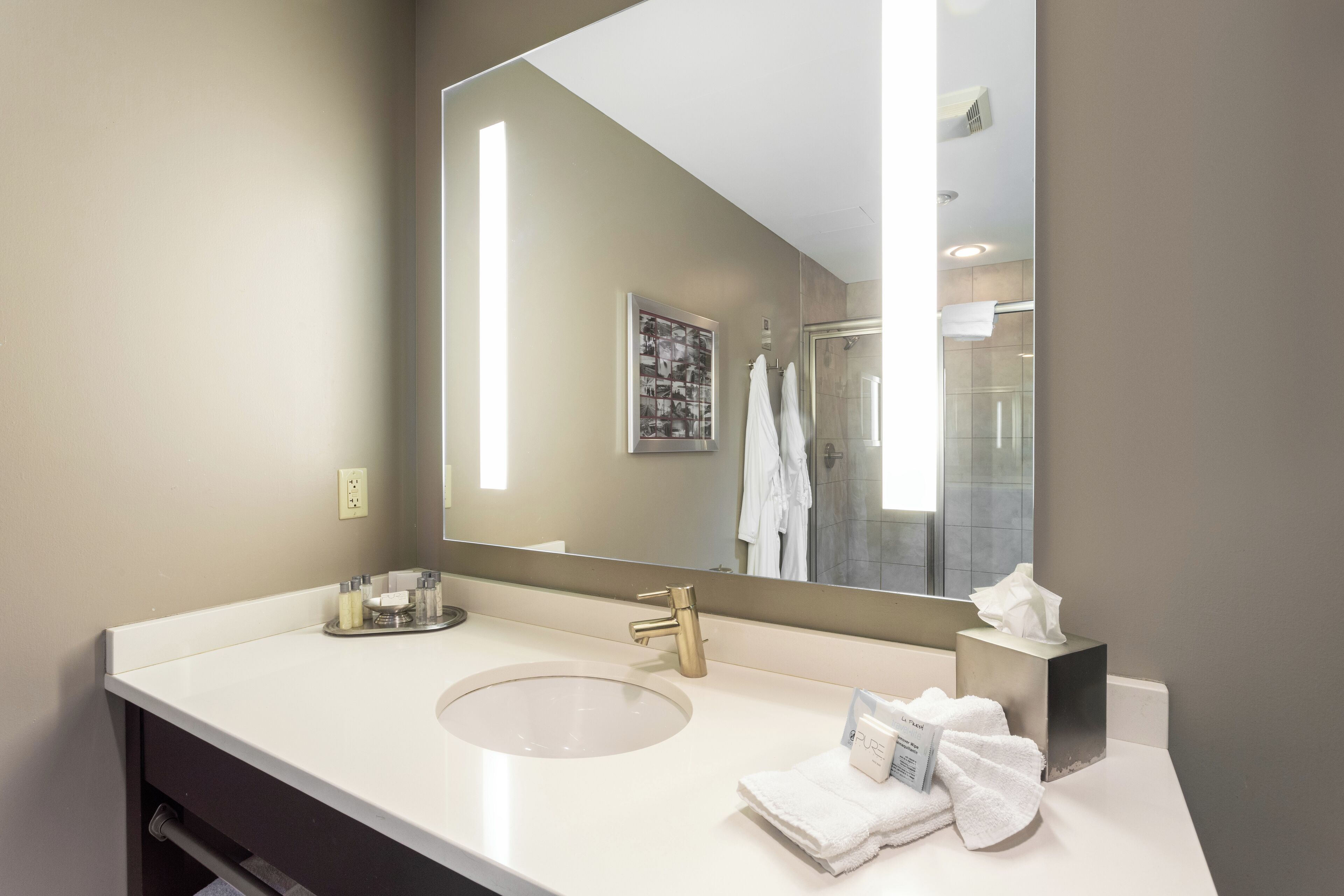 A modern bathroom with a large mirror, a sink, and a towel rack.