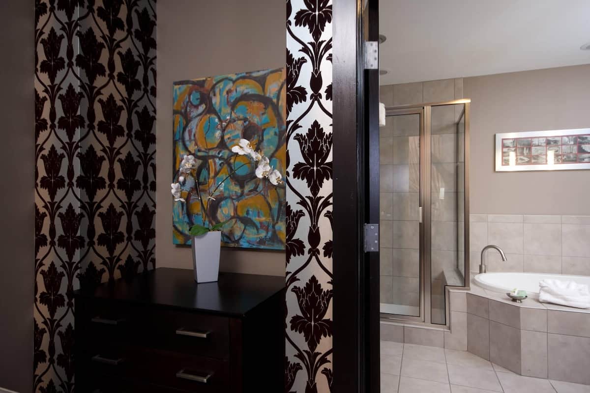 A modern bathroom with a dark wooden vanity, a glass shower enclosure, and a large abstract painting on the wall.