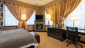 A hotel room with a bed, a desk, a chair, a fireplace, and curtains. - The Giacomo Niagara Falls NY, an Ascend Collection Hotel (Niagara Falls)