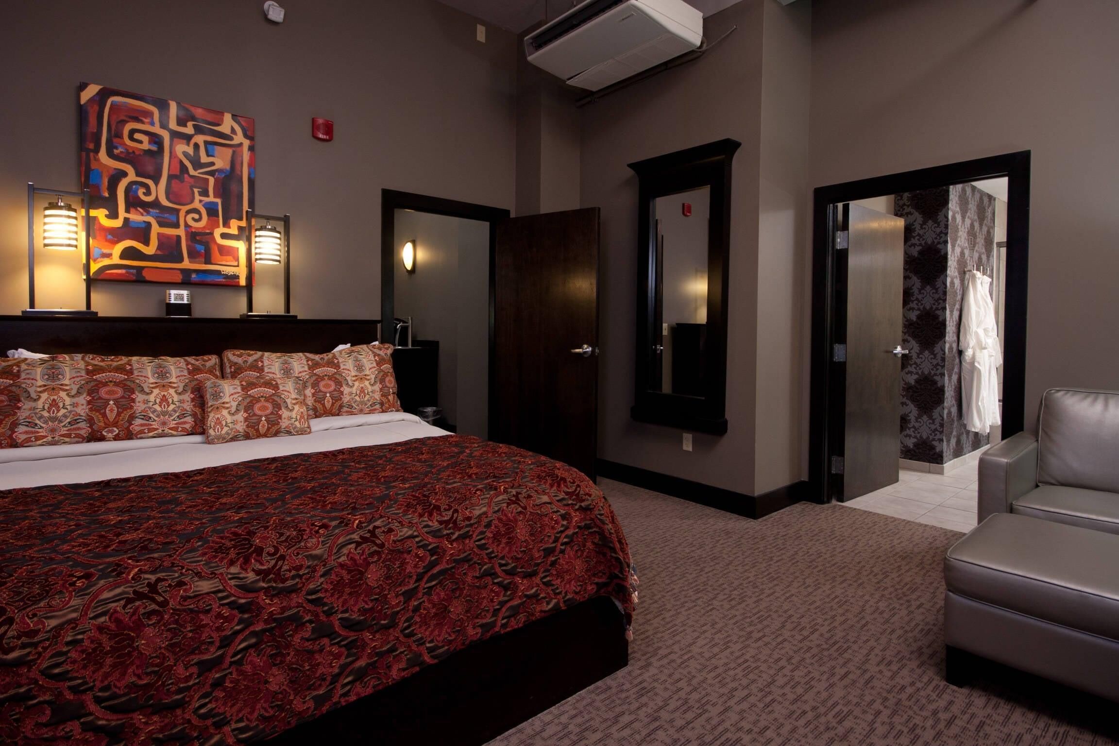 Une chambre d’hôtel avec un grand lit, un canapé, un miroir et un tableau au mur.