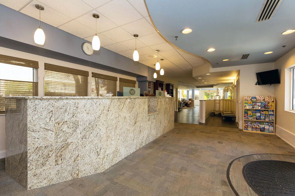 A reception area with a marble counter, pendant lighting, a clock, and a television on the wall.