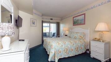A bedroom with a bed, bedside tables, a dresser, a TV, and a window.