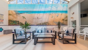 Un vestíbulo amplio con un mural de playa, asientos cómodos y un techo alto con tragaluces.