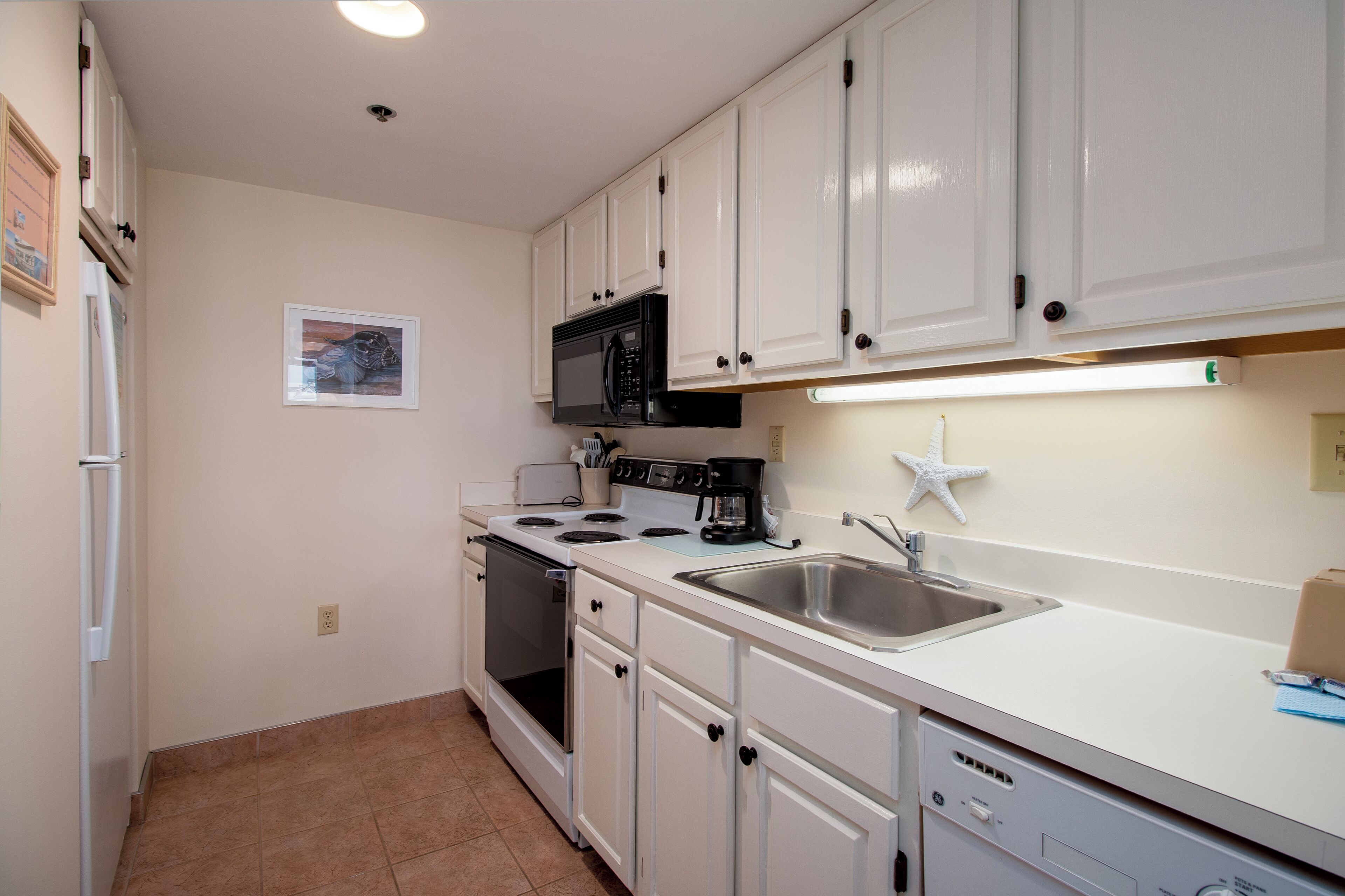 A kitchen with white cabinets, a microwave, stove, and a dishwasher.