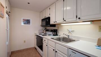 A kitchen with white cabinets, a microwave, stove, and a dishwasher.